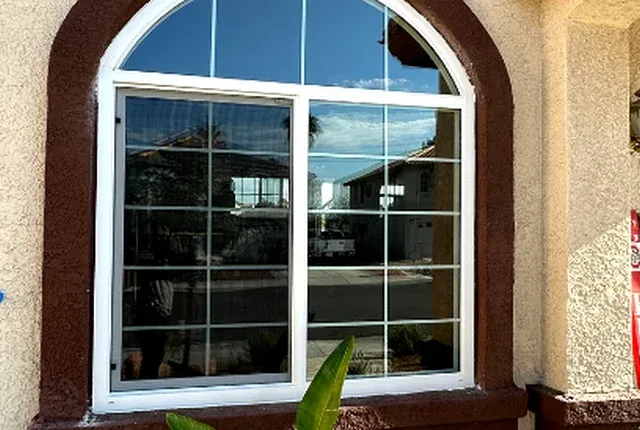 Arched window with white frame and reddish stucco surround