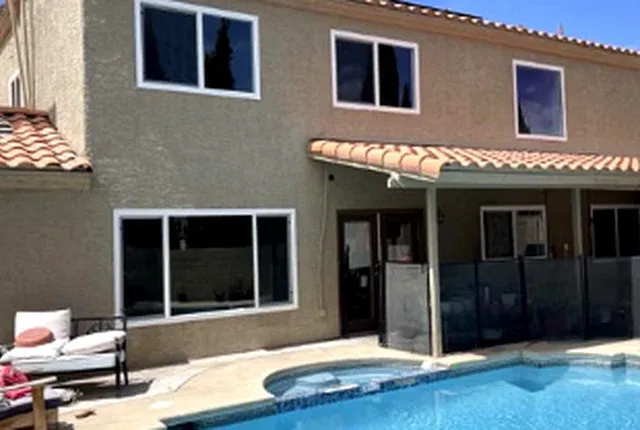 Two-story home exterior with consistent new white windows and a pool